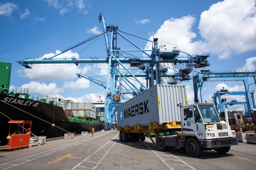 Truck carrying a container beneath gantry cranes at the Port of Mombasa