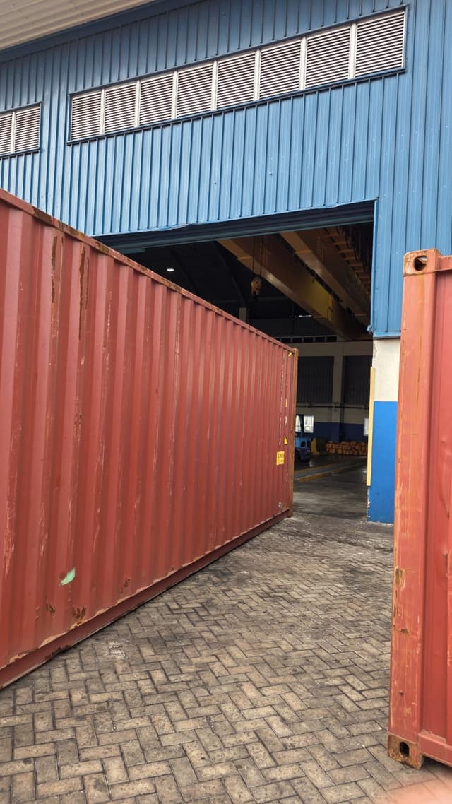 Two containers standing at the door of a warehouse